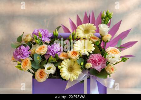 Der Blumenstrauß liegt anmutig in einer luxuriösen lila Box mit einer Mischung aus Farben und Texturen. Stockfoto