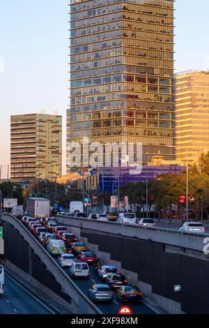 Dichter Verkehr auf einer Autobahn mit modernen Wolkenkratzern und Bäumen im Hintergrund bei Sonnenuntergang, Hospitalet de Llobregat, Barcelona, Katalonien, Spanien Stockfoto