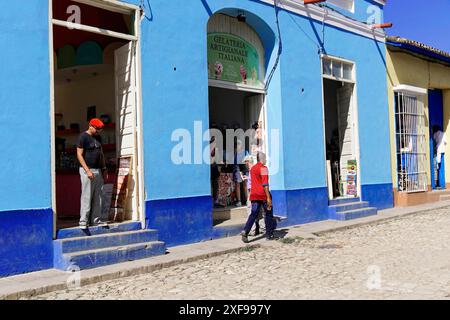 Trinidad, Kuba, Grosse Antillen, Karibik, Mittelamerika, Amerika, Szene in einer kubanischen Gasse mit blauen Gebäuden und Menschen, die vorbeilaufen Stockfoto