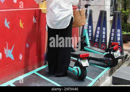 TOKIO, JAPAN - 16. Juni 2024: Person, die einen Luup-Mietwagen-E-Scooter mietet, parkt an einem farbenfrohen Gebäude in Tokios Meguro-Gegend. Stockfoto