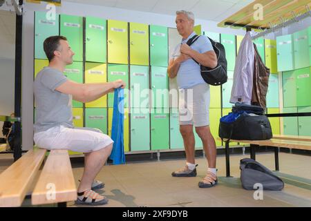 Zwei Männer benutzen Schließfächer in der seitlichen Ansicht des Fitnessstudios Stockfoto