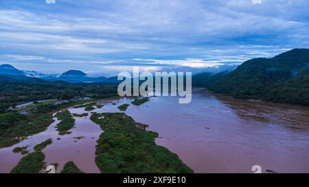 Aus der Vogelperspektive auf den mächtigen Mekong, der sich morgens während der Regenzeit vor den üppigen grünen Bergen schlängelt. Stockfoto