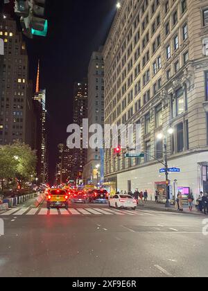 Straße bei Nacht in einer Stadt mit hohen Gebäuden, beleuchteten Ampeln und geschäftigen Autos, New York, USA Stockfoto