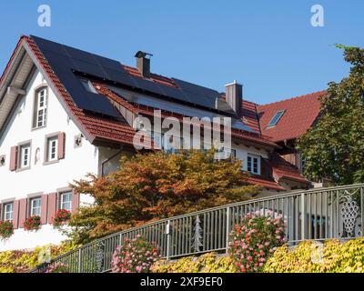 Ein modernes Haus mit Sonnenkollektoren und Blumen vor einem Zierzaun an einem sonnigen Tag, freudenstadt, Schwarzwald, deutschland Stockfoto