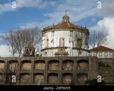 Großes rundes Gebäude mit roter Kuppel und weißen Wänden, umgeben von Bäumen und Steinmauern unter blauem Himmel, porto, portugal Stockfoto