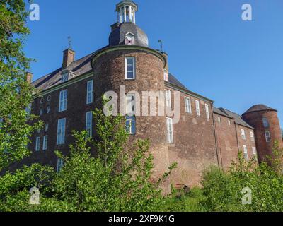 Großes Schloss mit runden Backsteintürmen und vielen Fenstern umgeben von grüner Natur vor blauem Himmel, hamminkeln, deutschland Stockfoto