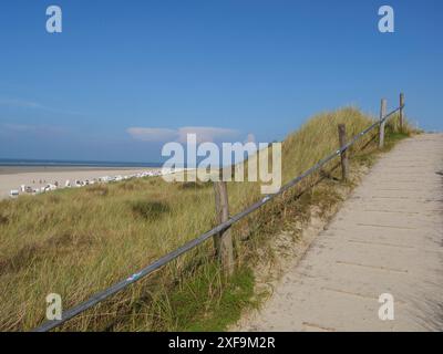 Gepflegter Weg mit Holzgeländern führt durch grasbewachsene Dünen hinunter zum breiten Sandstrand Spiekeroog, Nordsee, Deutschland Stockfoto