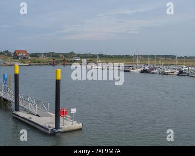 Ein ruhiger Hafen mit Segelbooten, einem Dock und Häusern im Hintergrund unter bewölktem Himmel, Spiekeroog, Nordsee, deutschland Stockfoto