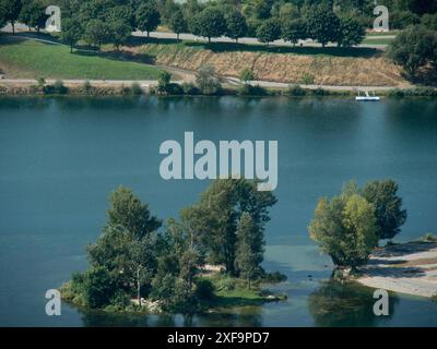 Kleine bewaldete Insel in einem Fluss mit ruhigem Wasser und Bäumen entlang der Küste, Wien, Österreich Stockfoto