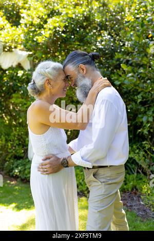 Ältere Braut und Bräutigam umarmen und lächeln im Garten, bei der Hochzeit Stockfoto