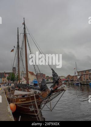 Ein großes Segelboot liegt im Hafen, umgeben von Wasser und Gebäuden unter bewölktem Himmel, Wismar, Ostsee, Deutschland Stockfoto