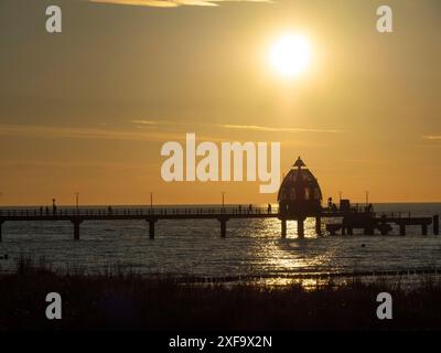 Der strahlende Sonnenuntergang taucht den Bootssteg und das Meer in goldenen Farben, ahrenshoop, zingst, Ostsee, Deutschland Stockfoto