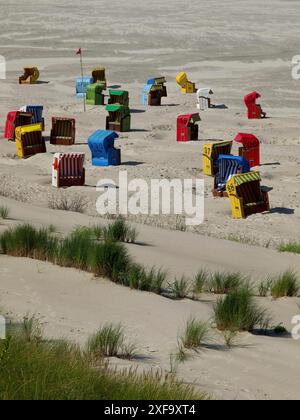 Verstreute bunte Liegen am Sandstrand, grasbewachsene Dünen und Meer im Hintergrund, Juist, Ostfriesland, Deutschland Stockfoto