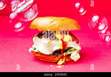 Asturischer Beef Burger. Burger Brioche Brot, Zwiebeln, Becom Käse, Senf, Ketchup, auf rotem Hintergrund. Spanien Stockfoto