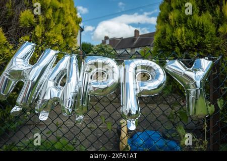 Silberne Happy Birthday-Worte aus aufblasbaren Ballons am Gartenzaun in england großbritannien. Stockfoto