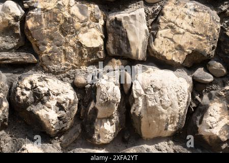 Nahaufnahme der Textur der alten Steinmauer mit großen Felsbrocken aus Kalkstein in verschiedenen Pastellfarben. Stockfoto