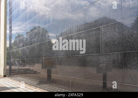 Schwarze Marmorwand eines Gebäudes in der Stadt, reflektiert den blauen, leicht bewölkten Himmel und die gegenüberliegende Seite des Ortes, wie ein anderes Gebäude, Stai Stockfoto