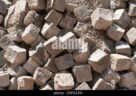 Die Konsistenz von Kubikpflastersteinen, unregelmäßig angeordnet. Die Steine werden noch für Bauarbeiten verwendet. Stockfoto