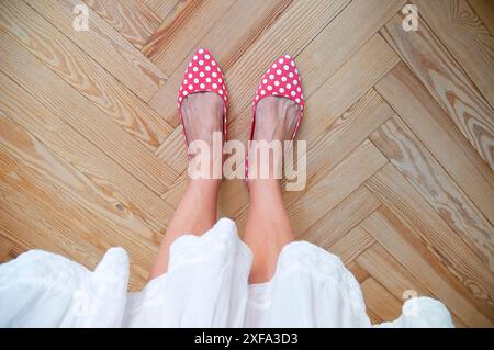 Frauenfüße auf Holzboden. Stockfoto
