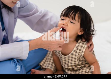 Arztspraymittel im Mund eines Kleinkindes. Behandlungskonzept für Baby-Halsschmerzen Stockfoto