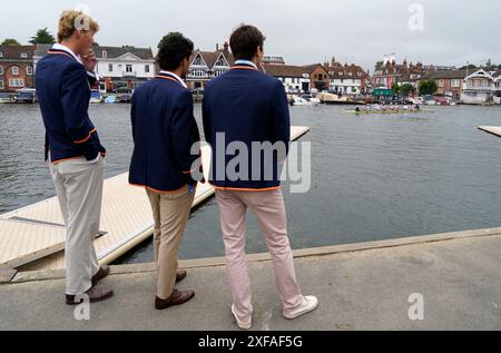 Die Menschen blicken von der Seite des Flusses aus, während sich eine Rudermannschaft von einem Ponton aus auf den Weg zur Startlinie macht, am Eröffnungstag der Henley Royal Regatta 2024 entlang der Themse in Henley-on-Thames, Oxfordshire. Bilddatum: Dienstag, 2. Juli 2024. Stockfoto