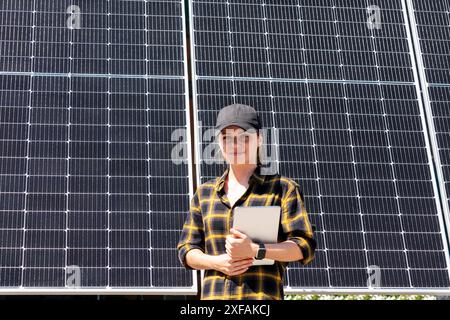 Porträt einer Inspektorin mit einem digitalen Tablet in der Hand steht vor einem großen industriellen Solarpanel Stockfoto