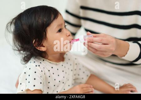 Mutter füttert ein flüssiges Medikament an kranke Kleinkinder mit Tropfer Stockfoto