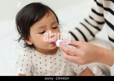 Mutter füttert ein flüssiges Medikament an kranke Kleinkinder mit Tropfer Stockfoto