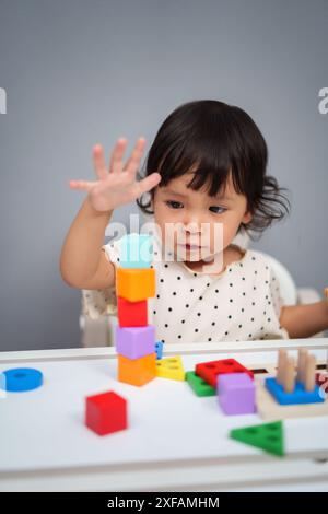 Kleinkind spielt ein Blockspielzeug, um Würfel auf dem Tisch zu stapeln Stockfoto