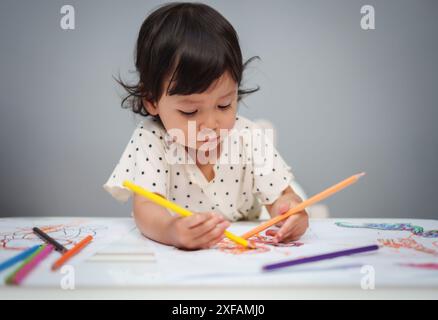 Kleinkind spielt und trainiert mit dem Farbstift auf dem Tisch Stockfoto