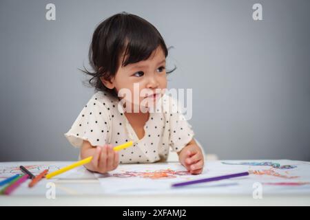 Kleinkind spielt und trainiert mit dem Farbstift auf dem Tisch Stockfoto