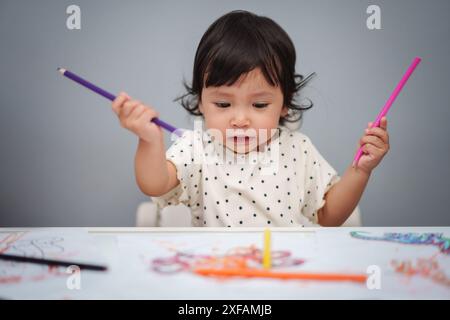 Kleinkind spielt und trainiert mit dem Farbstift auf dem Tisch Stockfoto