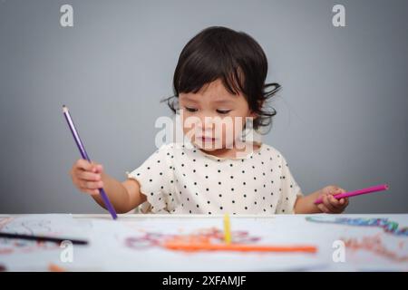 Kleinkind spielt und trainiert mit dem Farbstift auf dem Tisch Stockfoto