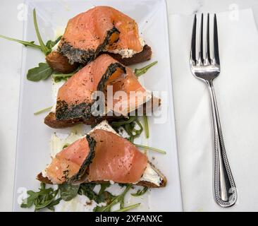 Kräuterlachslein auf Toast mit Frischkäse (Frühstück Gravlax offene Sandwiches) Rucola Zitronendrizzle (Dillkruste Fisch mit Kräutern) Toast Brot Stockfoto