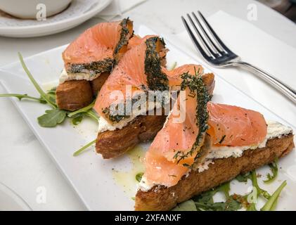 Kräuterlachslein auf Toast mit Frischkäse (Frühstück Gravlax offene Sandwiches) Rucola Zitronendrizzle (Dillkruste Fisch mit Kräutern) Toast Brot Stockfoto