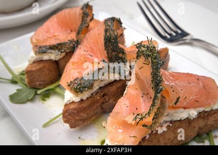 Kräuterlachslein auf Toast mit Frischkäse (Frühstück Gravlax offene Sandwiches) Rucola Zitronendrizzle (Dillkruste Fisch mit Kräutern) Toast Brot Stockfoto