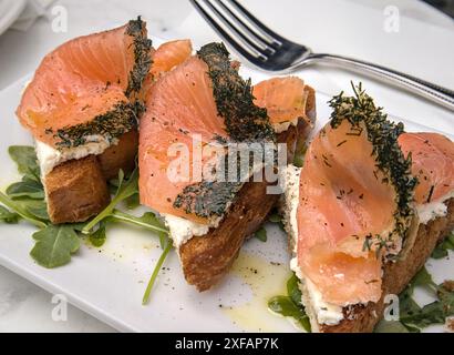 Kräuterlachslein auf Toast mit Frischkäse (Frühstück Gravlax offene Sandwiches) Rucola Zitronendrizzle (Dillkruste Fisch mit Kräutern) Toast Brot Stockfoto