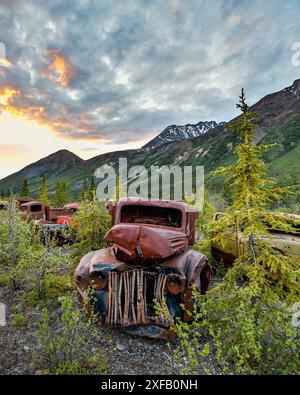 Ein alter, rostiger, alter Truck, eingebettet in die Wildnis mit Sommer-Bergkulisse. Aufgenommen im Yukon-Territorium, Kanada. Stockfoto