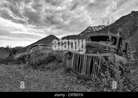 Ein alter, rostiger, alter Truck, eingebettet in die Wildnis mit Sommer-Berguntergang und Sonnenuntergang. In Schwarzweiß, Graustufen-Design. Stockfoto