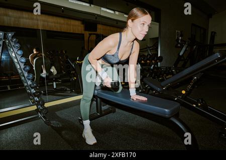 Junge sportliche Frau, die mit Langhanteln Eisen pumpt Stockfoto