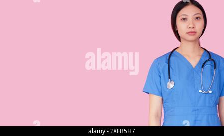 Mediziner. Gesundheitspersonal. Selbstbewusste Ärztin in blauer Uniform mit Stethoskop isoliert auf rosa Leerraumhintergrund. Stockfoto