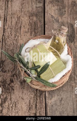 Seifenriegel aus natürlichem Olivenöl und Flasche aus Olivenöl in einem Korb auf Holztisch Stockfoto