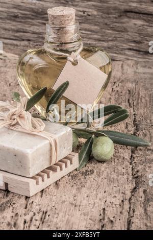 Natürliche Seifenstange und Olivenöl in einer herzförmigen Flasche auf Holztisch Stockfoto