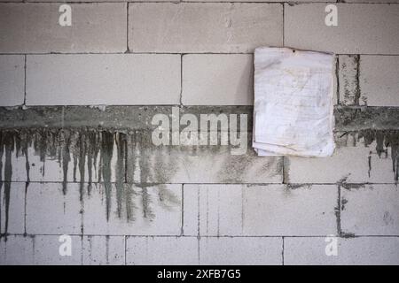 Blaues Papier hängt an der Ziegelwand auf der Baustelle des Hauses Stockfoto