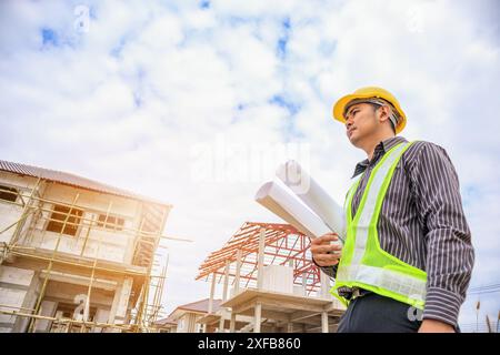 Asiatischer Bauingenieur in Schutzhelm und Bauplanpapier auf der Baustelle Stockfoto