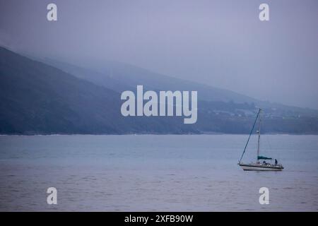 Eine Segelyacht an einem kalten und nebeligen Abend in der Cardigan Bay in Aberystwyth entlang der walisischen Küste. Stockfoto