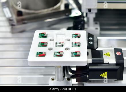 Fabrikmaschinen bei der Arbeit wird Eine kleine Leiterplatte in einem automatisierten Roboterarm montiert Stockfoto