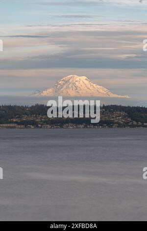 Warme Farbtöne bei Sonnenuntergang erzeugen ein wunderschönes Porträt des Mount Rainier im Bundesstaat Washington mit Reflexionen im Wasser. Stockfoto