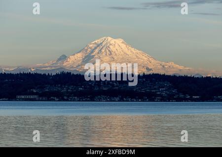 Warme Farbtöne bei Sonnenuntergang erzeugen ein wunderschönes Porträt des Mount Rainier im Bundesstaat Washington mit Reflexionen im Wasser. Stockfoto