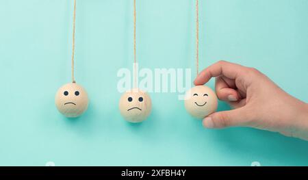 Glückliches lächelndes Gesicht verbreitete Glück auf traurige Gesichter, newton Wiege Konzept, mentale Gesundheit und Einstellung, positiver und negativer Geist, beeinflussen Emotionen Stockfoto